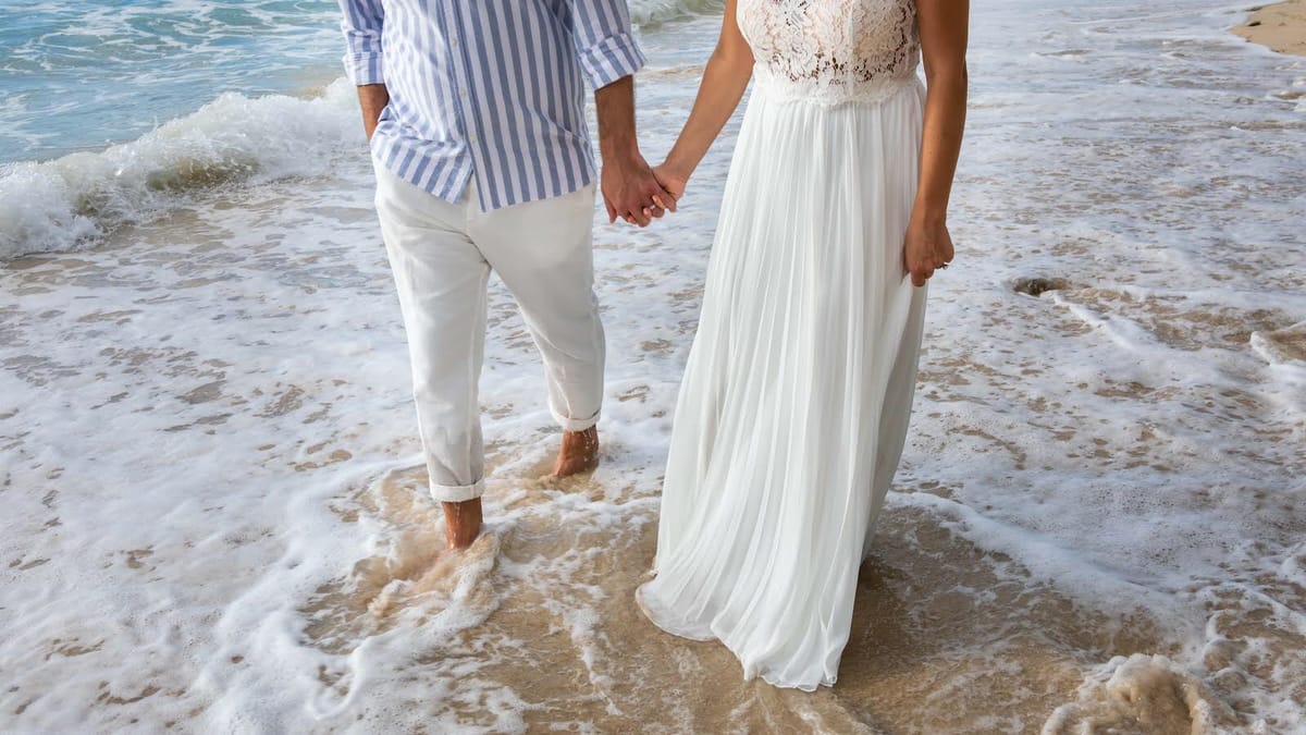 Couple walking hand in hand through the surf on a Barbados beach