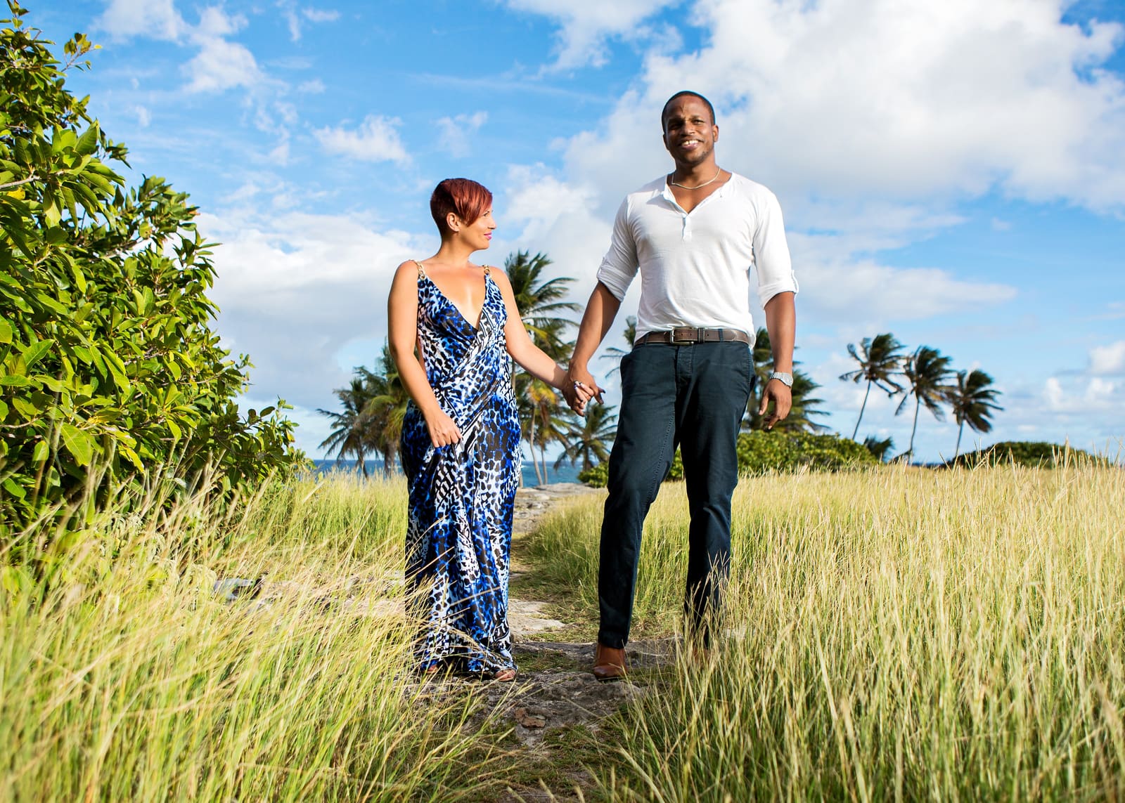 Couple holding hands on a grassy coastal path in Barbados