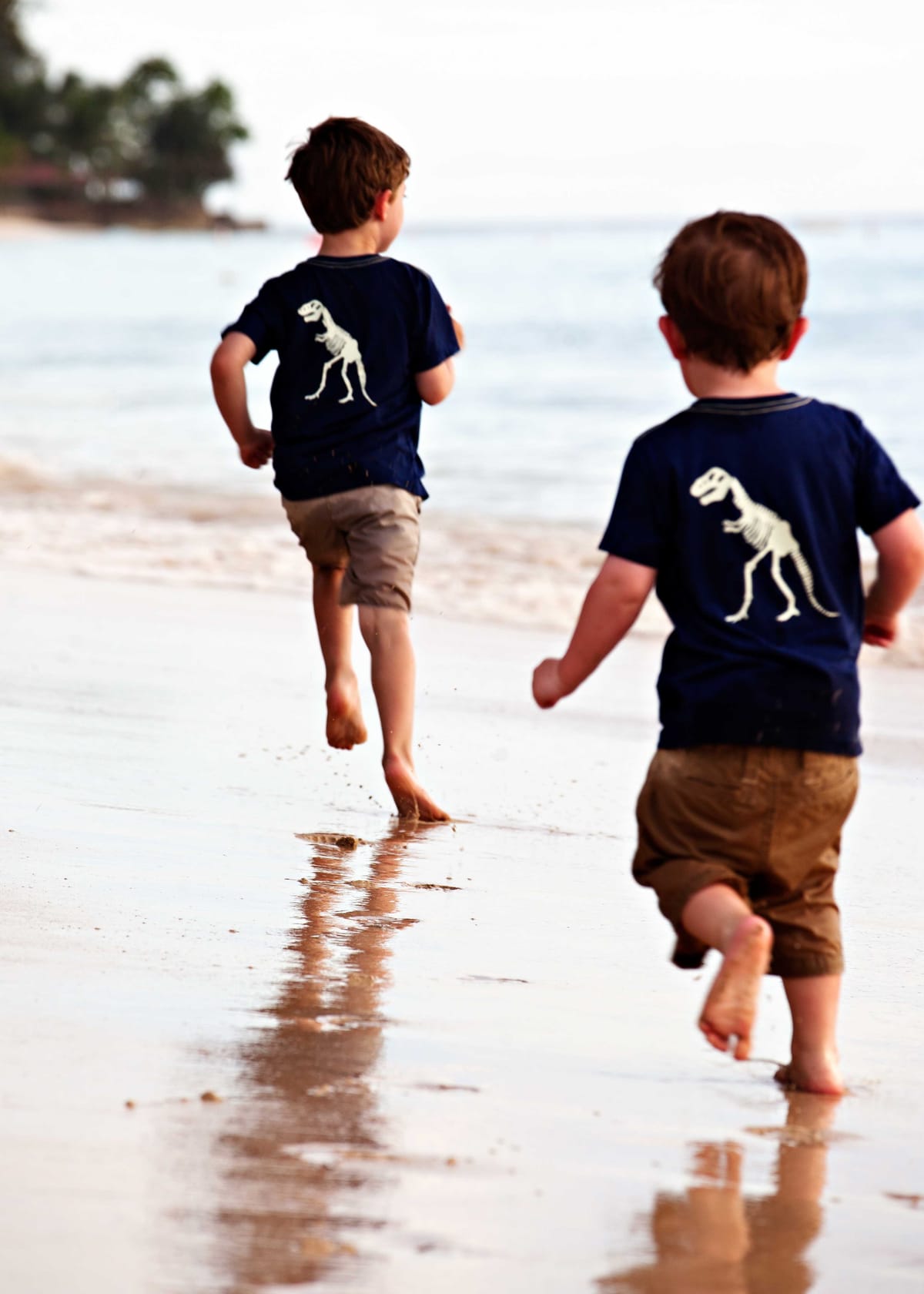 Two young boys running along the shoreline at a Barbados beach