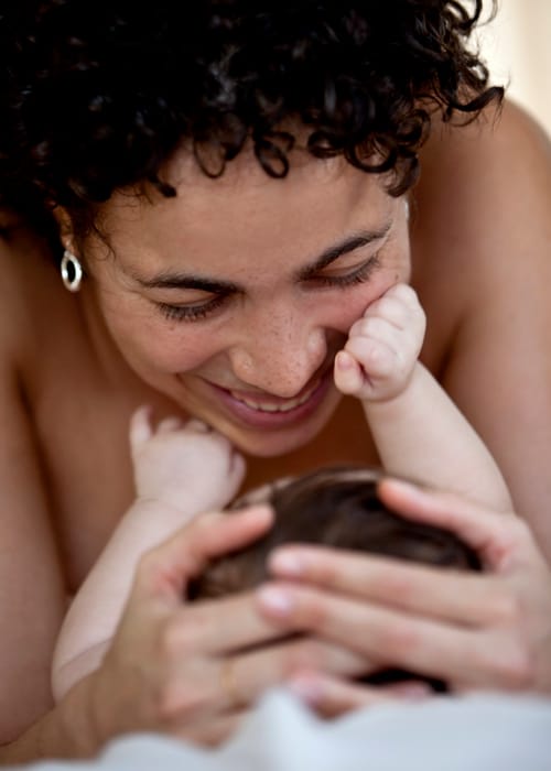 Mother smiling as her baby touches her face during a family portrait