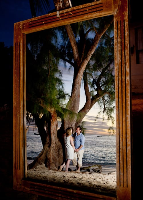 Couple beneath a coastal tree viewed through a decorative frame