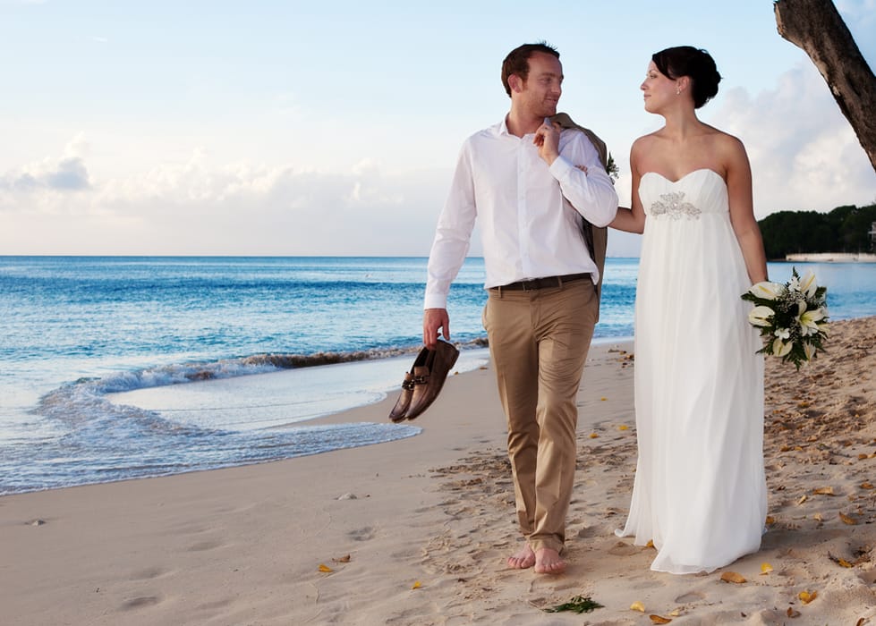 Groom kissing his bride on a Barbados beach at dusk