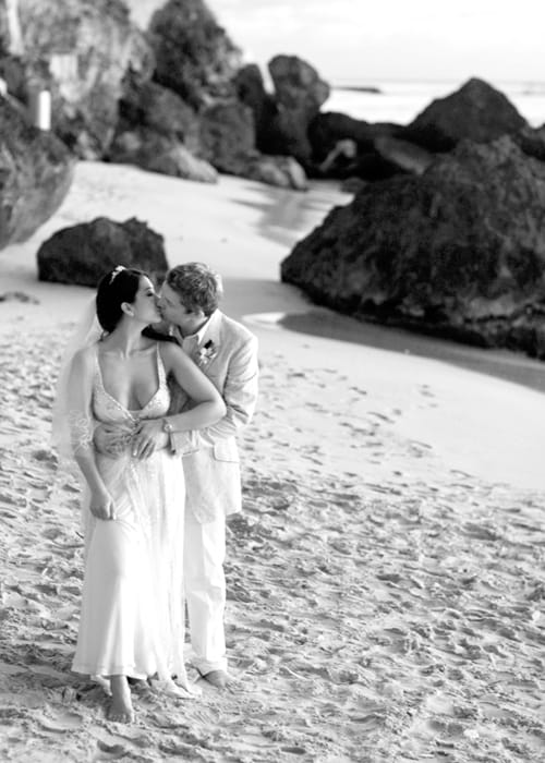 Newlyweds sharing a kiss in a black-and-white Barbados beach portrait