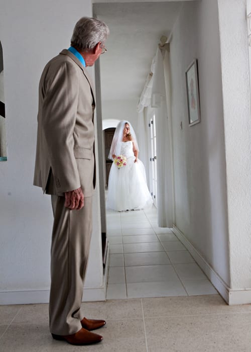 Bride holding a tropical red wedding bouquet on a sandy Barbados beach