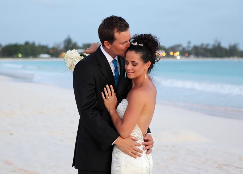 Groom kissing his bride on the forehead during a Barbados beach portrait