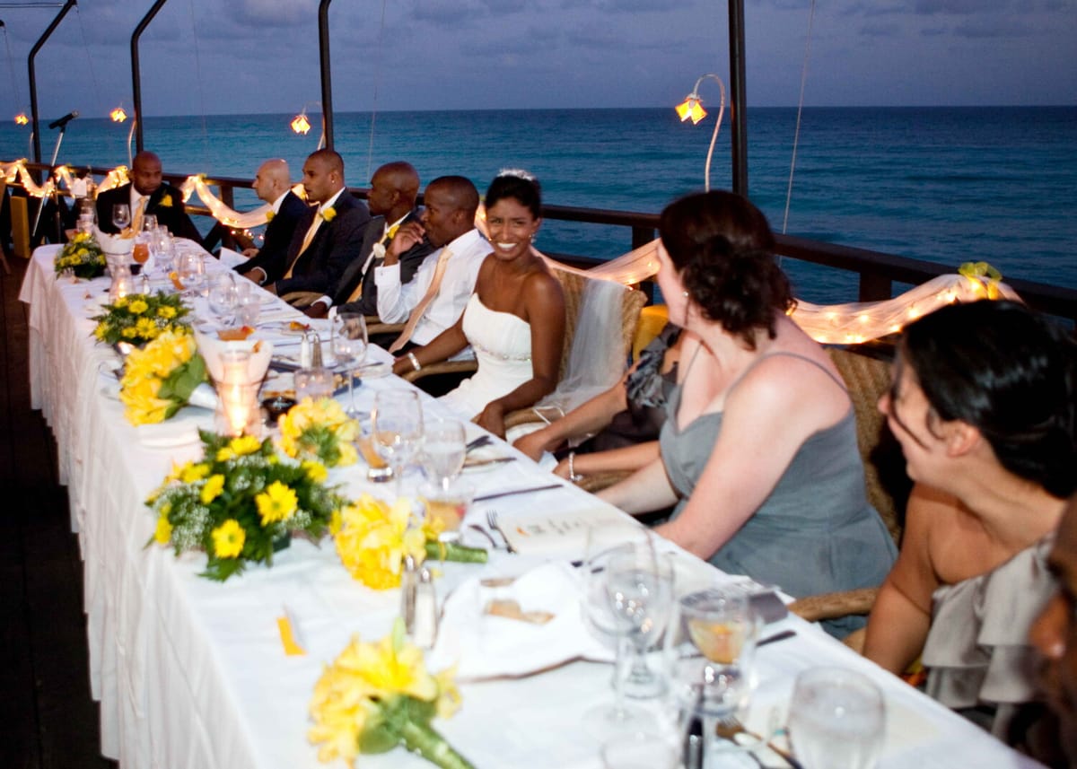 Bride smiling with her wedding party during an oceanfront reception