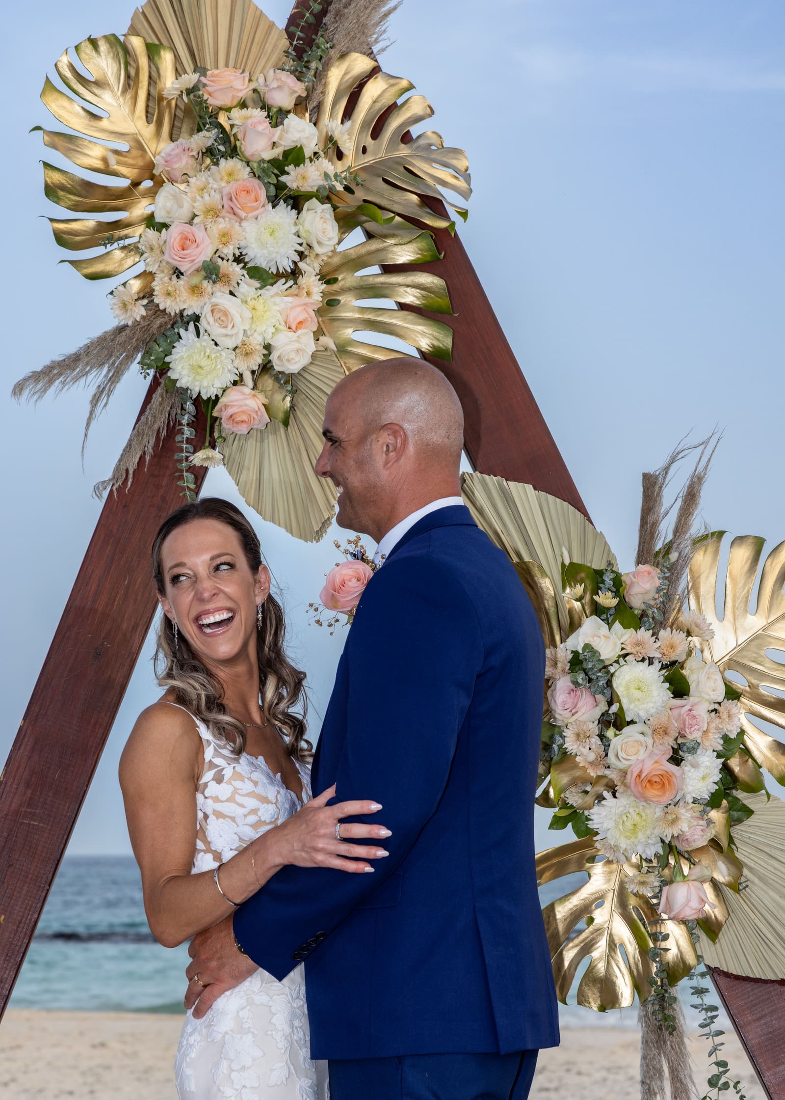 Bride and groom laughing beneath a floral arch, Barbados