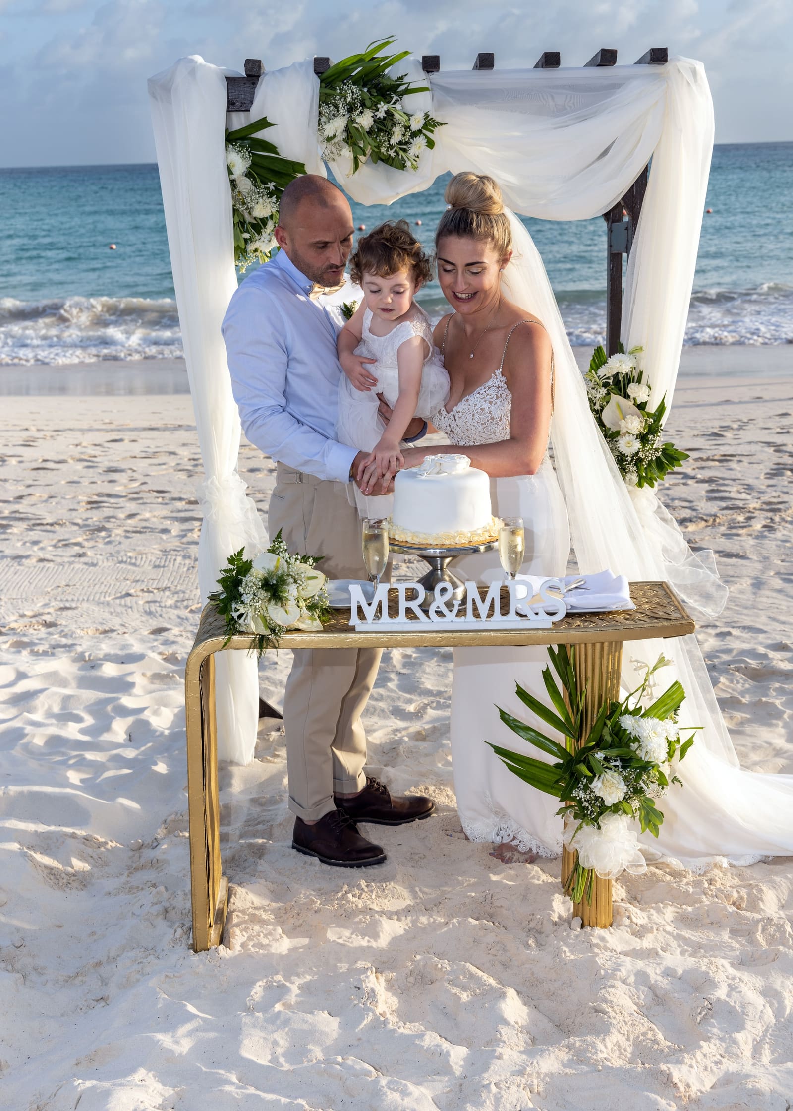 Couple cutting their cake at a beach table, Barbados