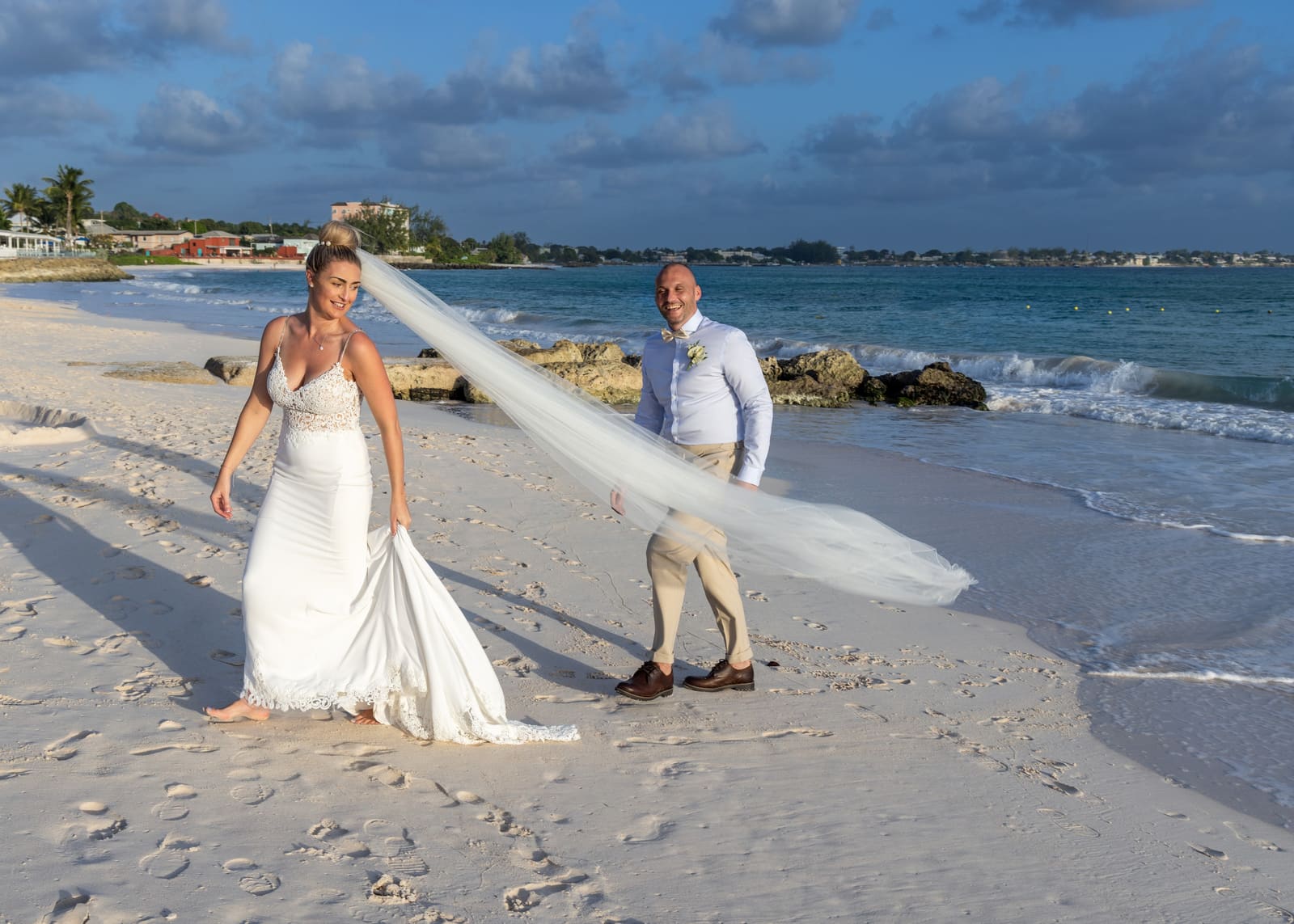 Bride walking toward the groom as her veil blows in the wind, Barbados