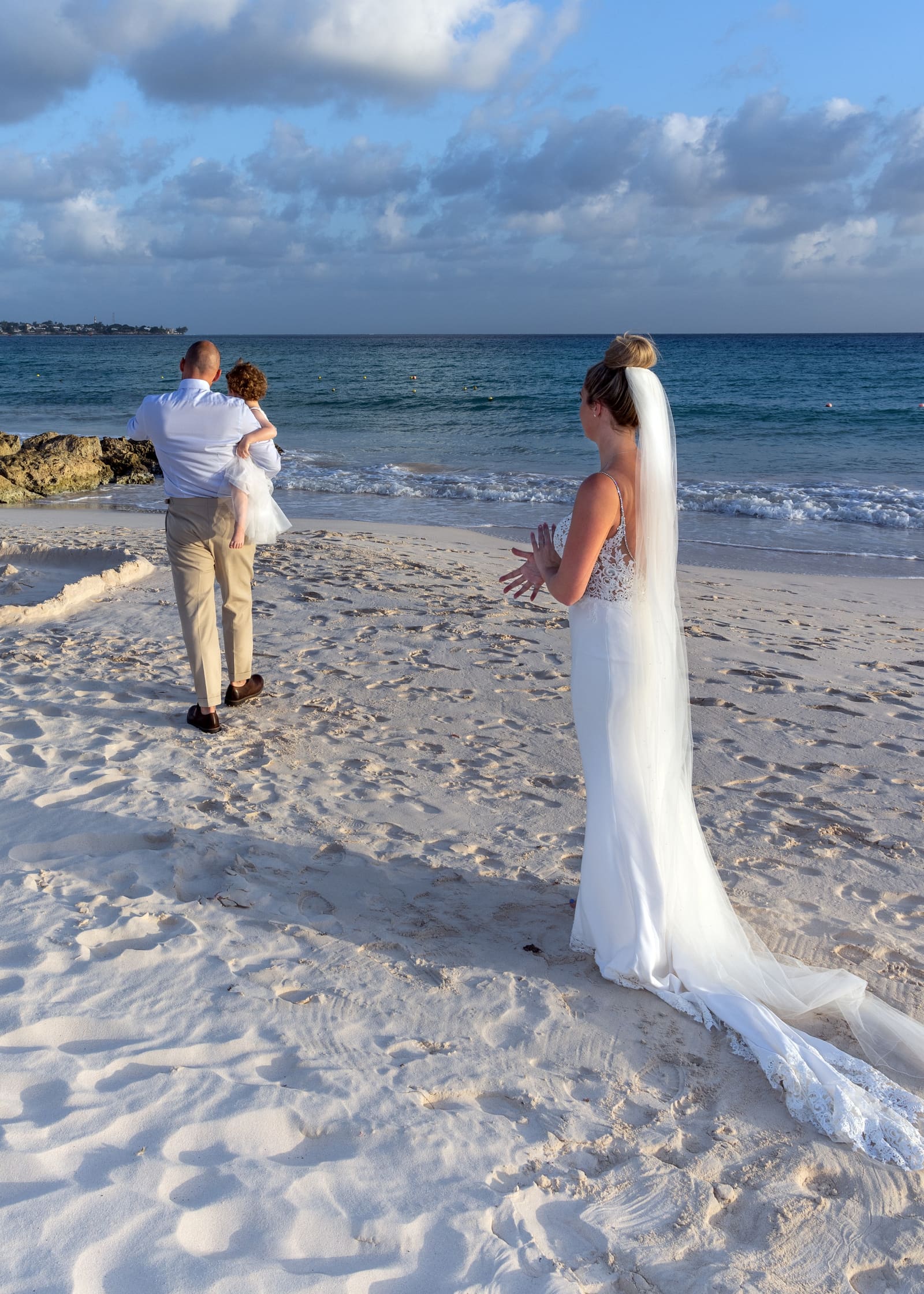 Bride and groom walking on the beach toward the sea, Barbados