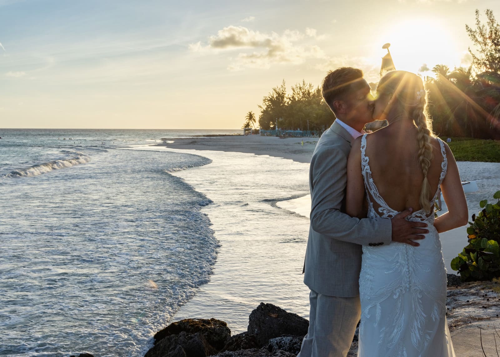 Couple embracing on the shore with the sun behind them, Barbados