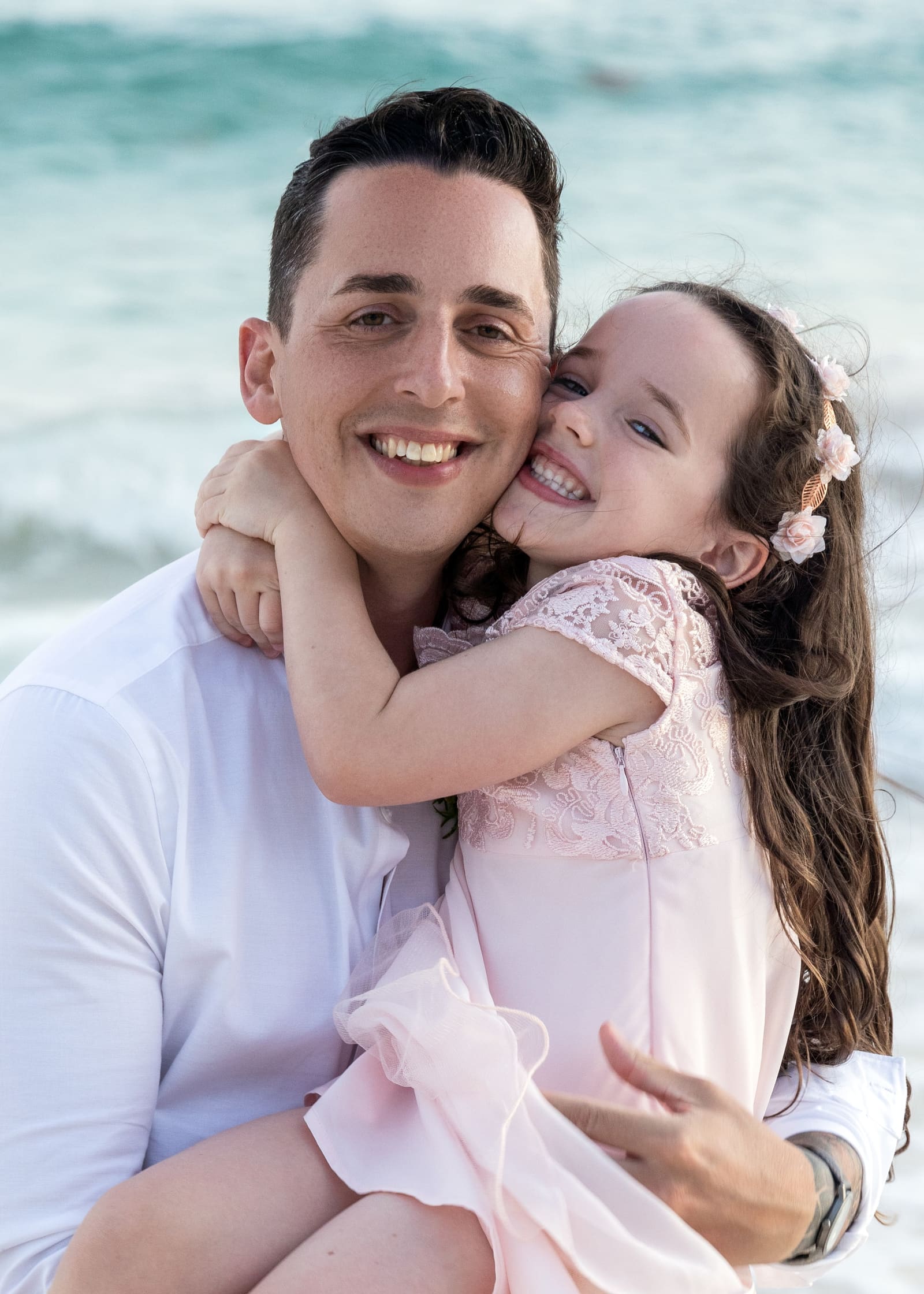 Groom hugging a young girl on the beach, Barbados