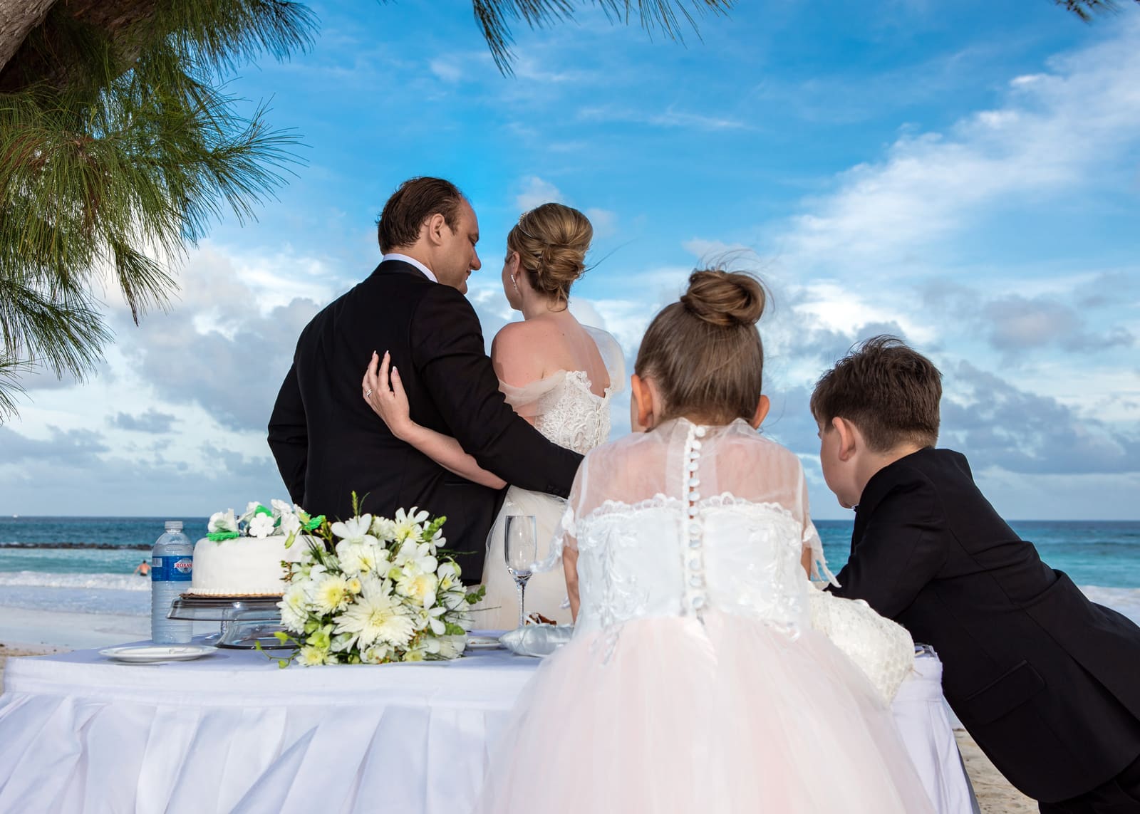 Couple and a young guest looking out to sea from the cake table, Barbados