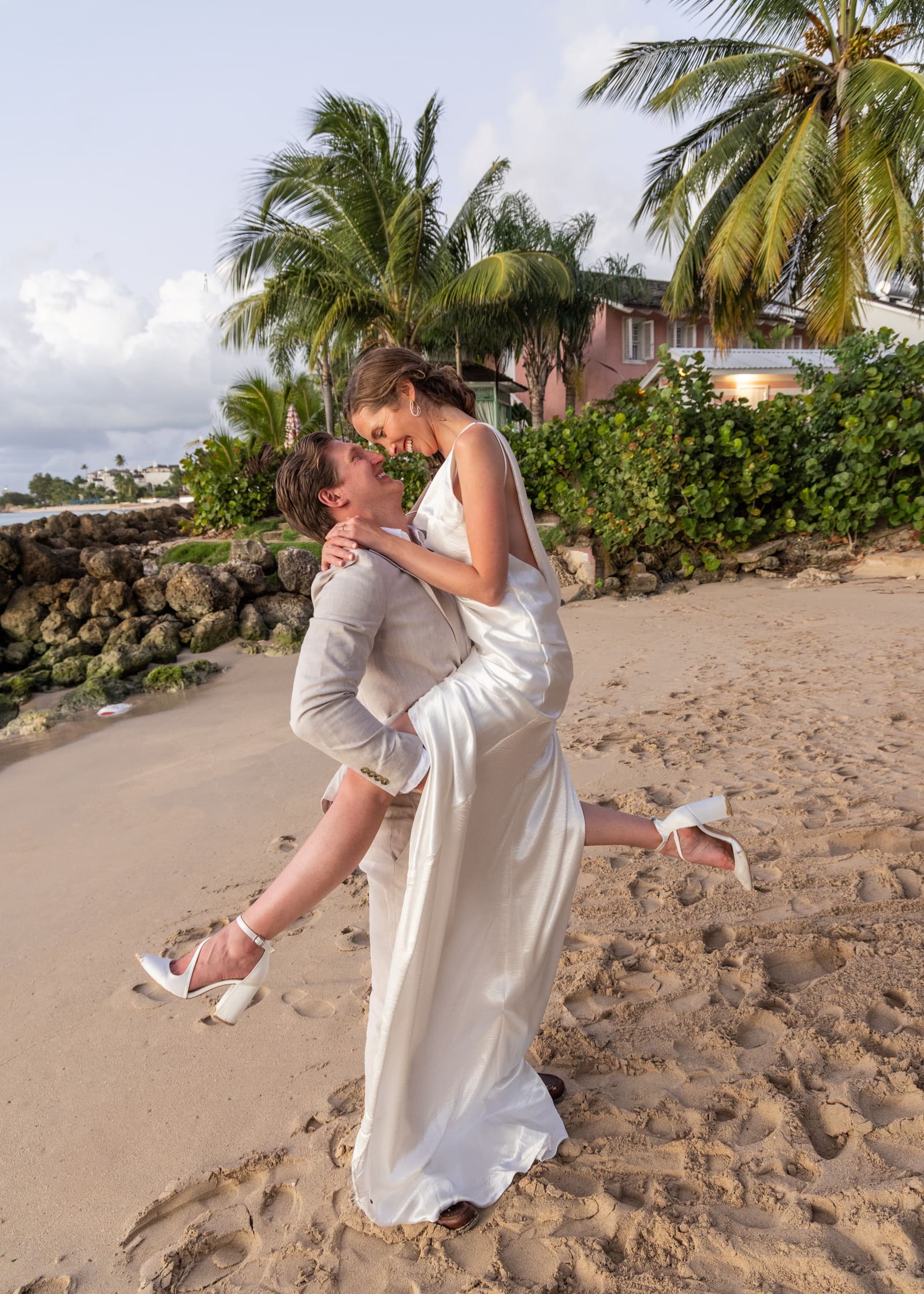 Groom lifting the bride for a kiss on the beach, Barbados